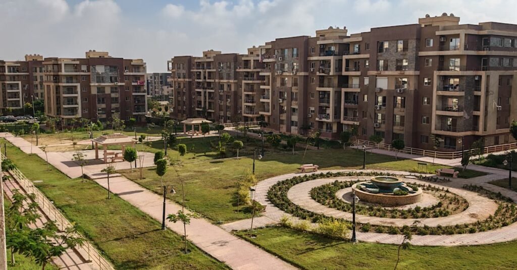 A scenic view of a modern apartment complex surrounded by lush greenery and clear blue skies.