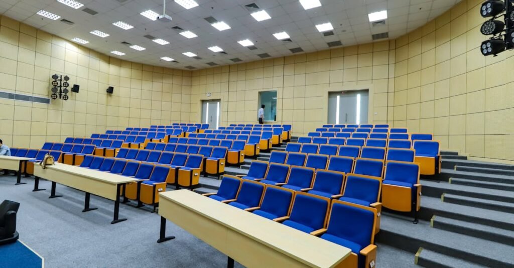 Spacious lecture hall with blue seats and desks ready for students.