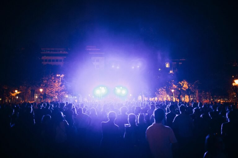 A lively outdoor concert scene at night with colorful lights and a large audience.